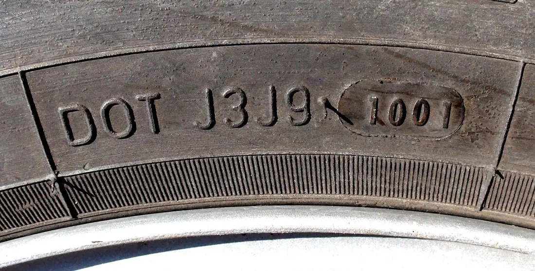 Tire sidewall molded with the letters DOT J3J9 and a four-digit date code, 1001, inside an oval.