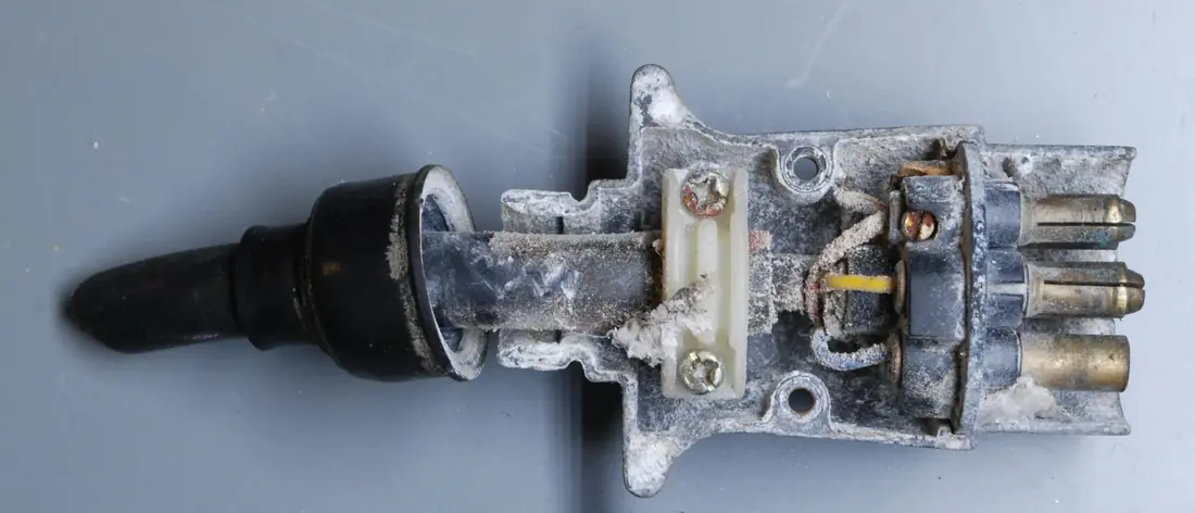 A 7-pin trailer plug opened up, its metal housing and pins coated in white corrosion.